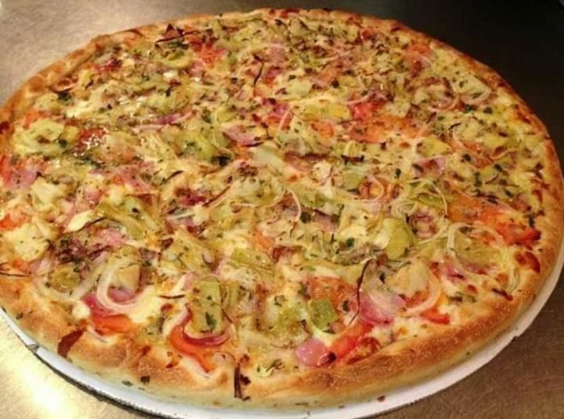 Large pizza with artichoke hearts, red onions, tomatoes, and melted cheese on a golden crust.